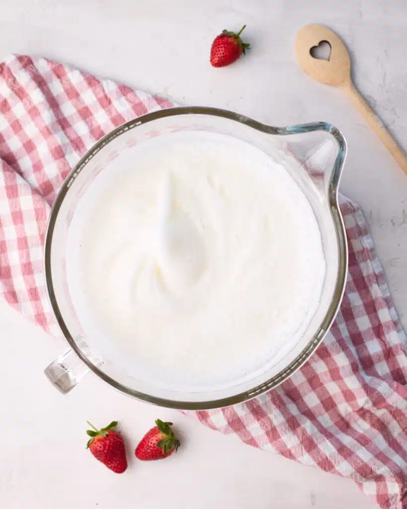 Egg whites whipped to soft peaks to make strawberry angel food cake.