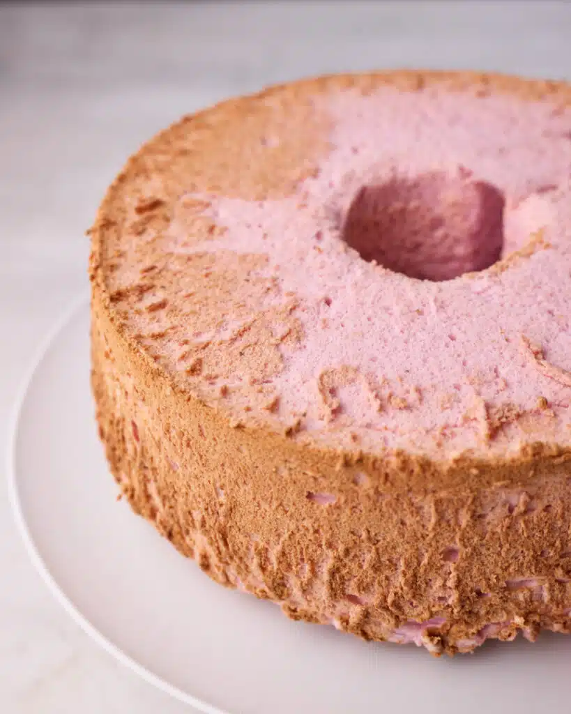 Strawberry angel food cake once removed from the pan, showing golden brown edges.