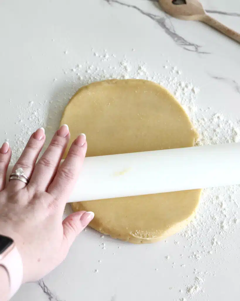 Rolling out shortcrust pastry with a rolling pin to make a tart shell.