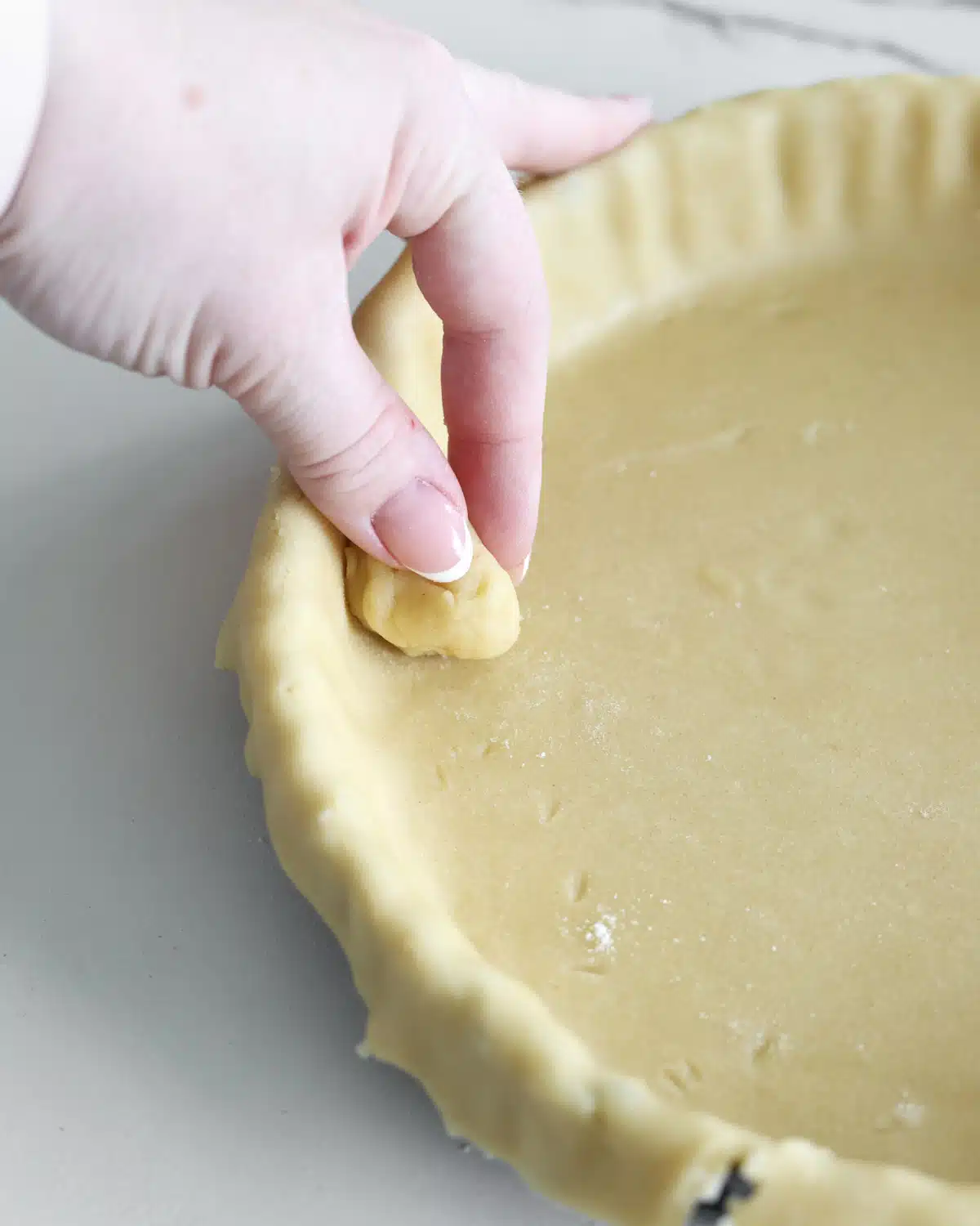 Using a ball of pastry to push down shortcrust pastry into the pan.
