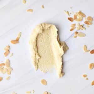 frangipane (almond cream) smeared onto a marble worktop with flaked almonds sprinkled all around it.