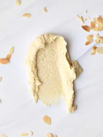 frangipane (almond cream) smeared onto a marble worktop with flaked almonds sprinkled all around it.