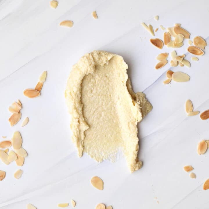 frangipane (almond cream) smeared onto a marble worktop with flaked almonds sprinkled all around it.