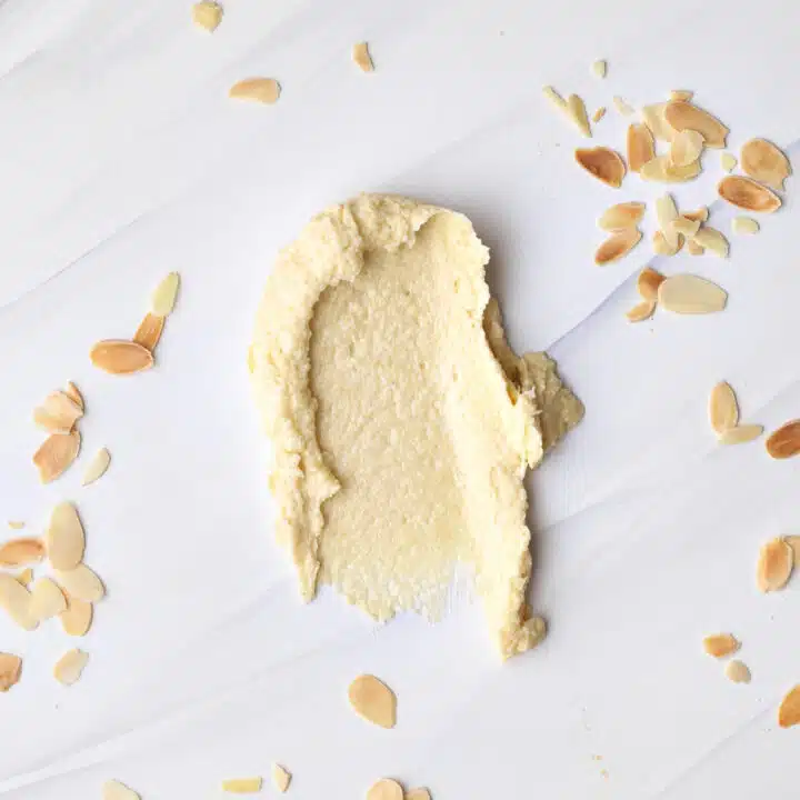 frangipane (almond cream) smeared onto a marble worktop with flaked almonds sprinkled all around it.