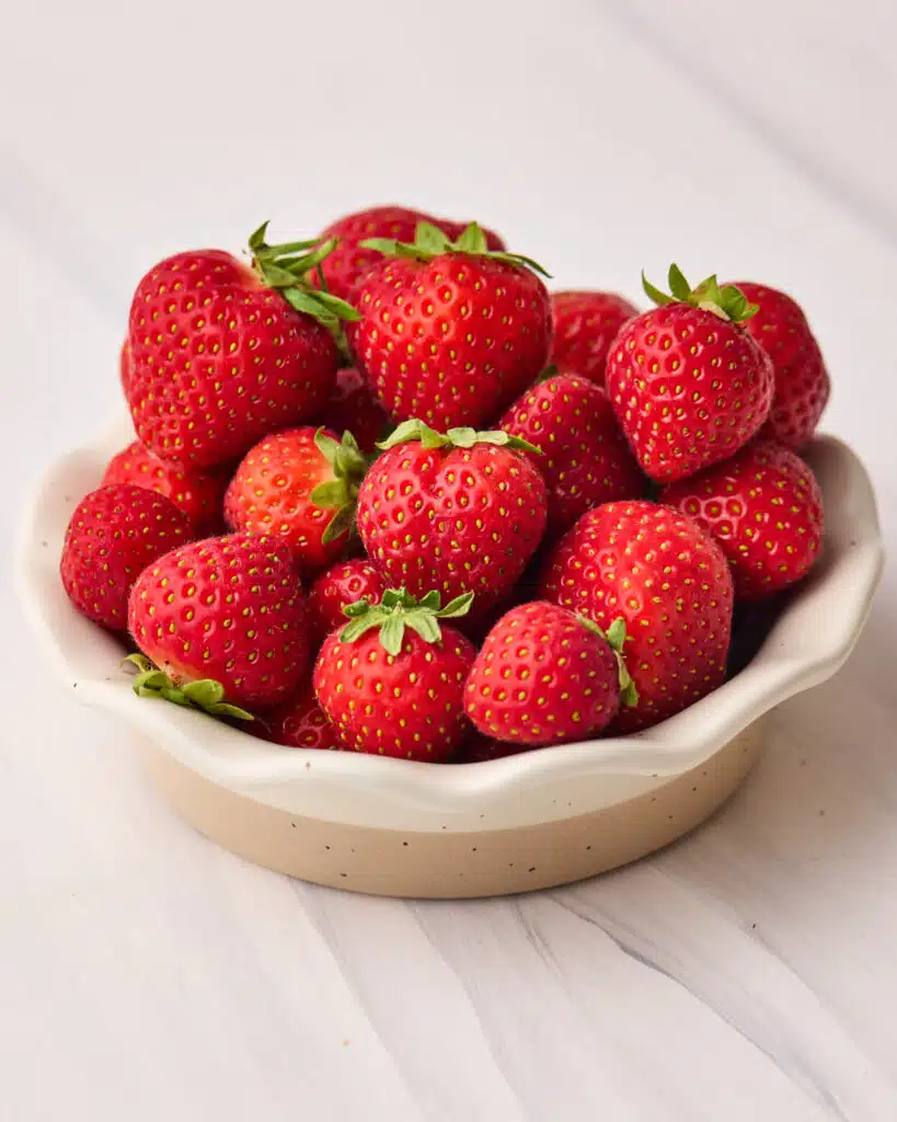 dish filled with fresh, ripe strawberries to make strawberries and cream. 