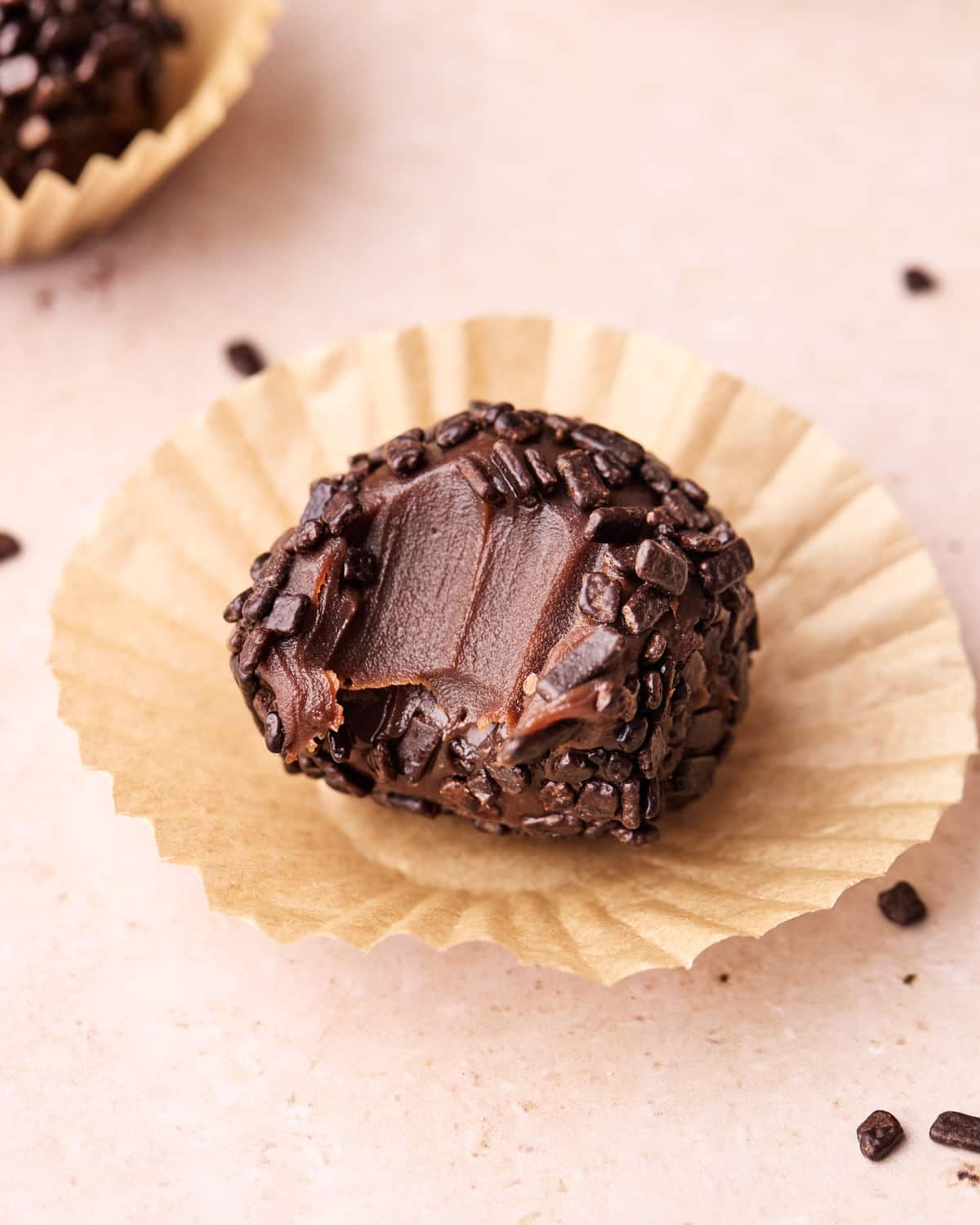 Single brigadeiro with a bite taken out of it to show the fudgy texture.