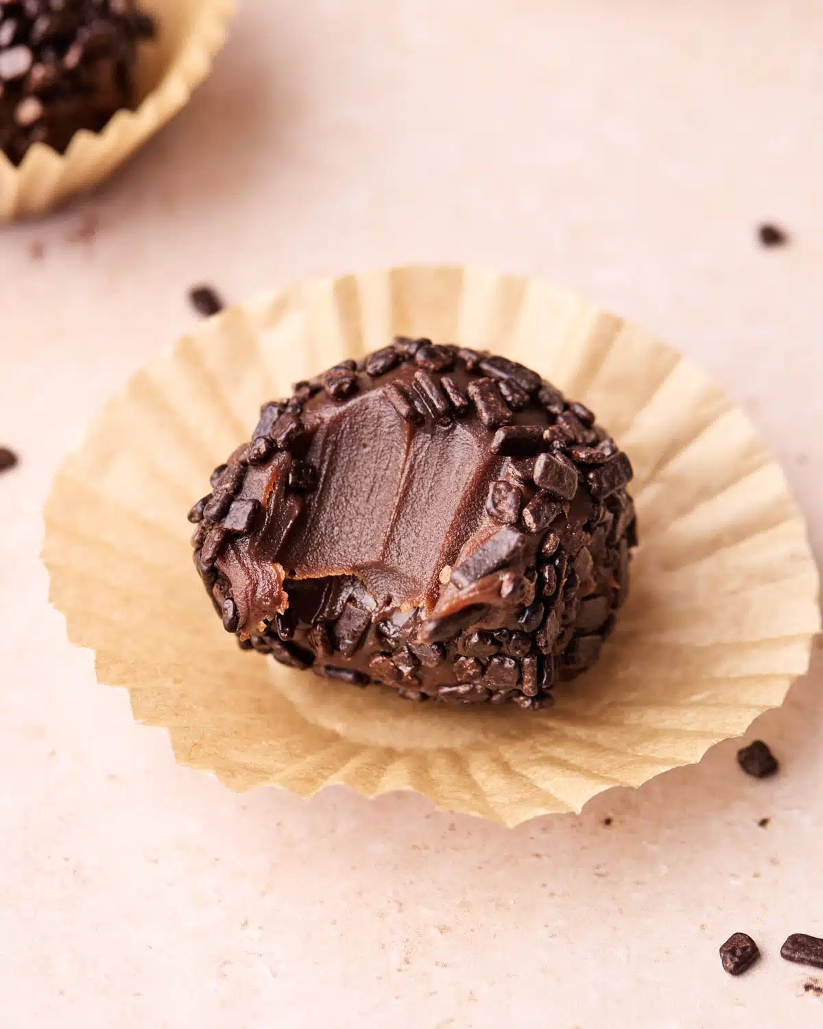 Single brigadeiro with a bite taken out of it to show the fudgy texture. 