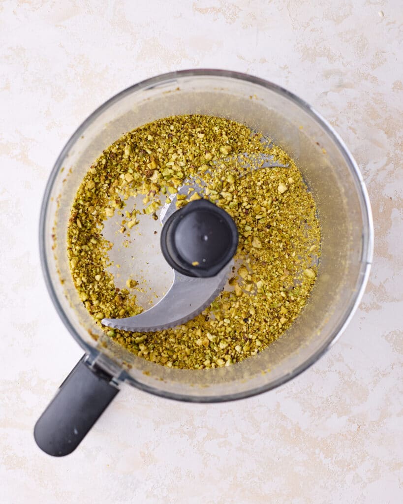 Chopping pistachios in a food processor to make pistachio cheesecake.