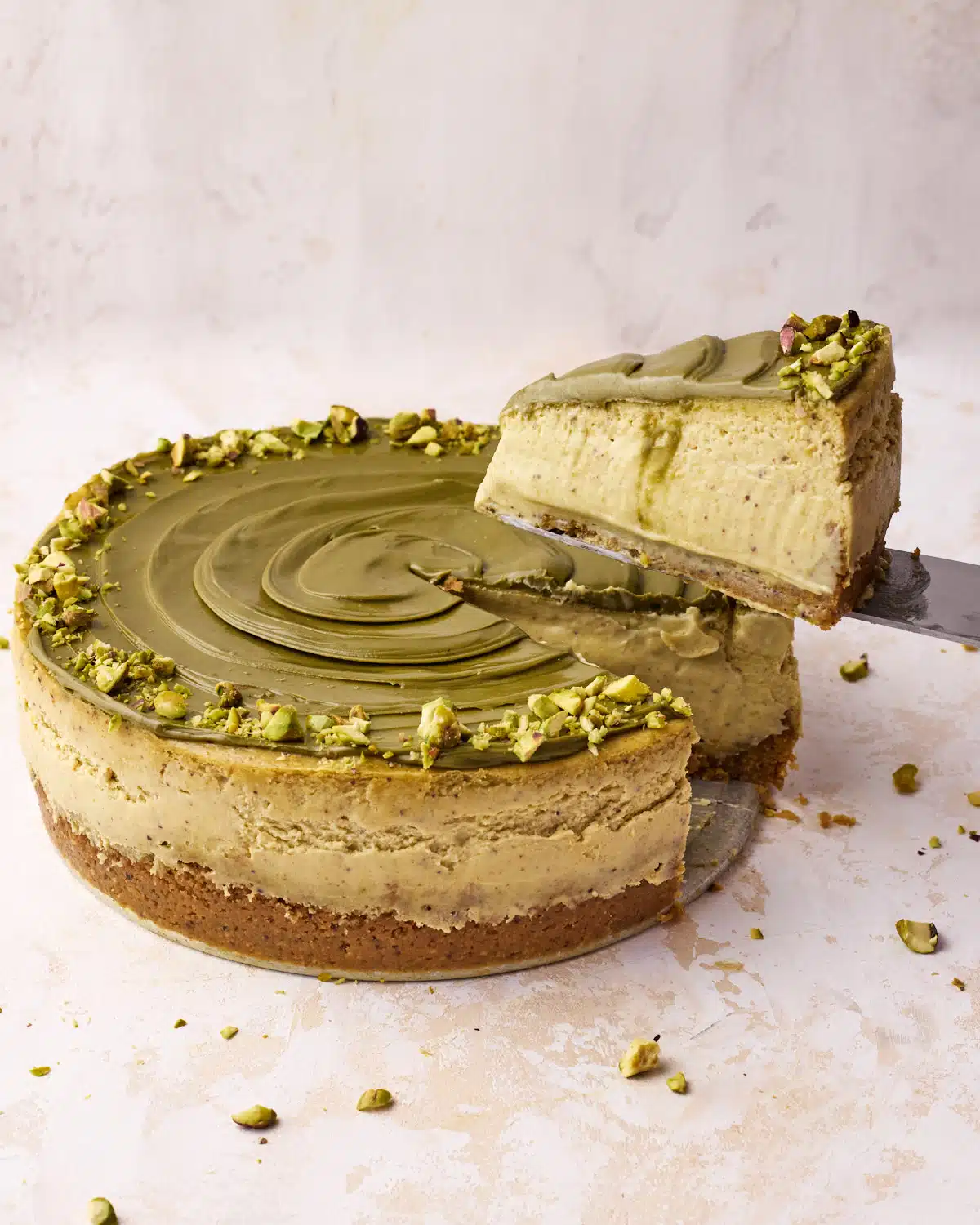 Pistachio cheesecake with a slice being taken out of it to show creamy texture. 