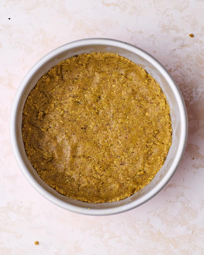 Pistachio graham cracker crust pressed into the bottom and sides of a cheesecake pan. 