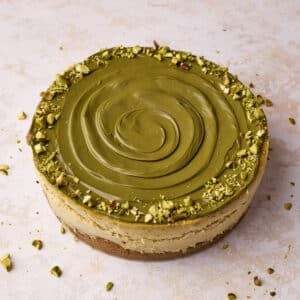 Pistachio cheesecake decorated with a swirl of pistachio cream and chopped pistachios around the outside.