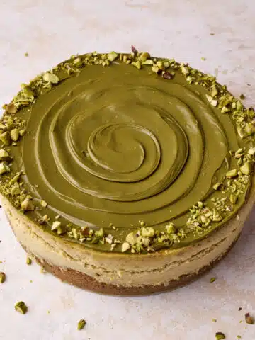 Pistachio cheesecake decorated with a swirl of pistachio cream and chopped pistachios around the outside.