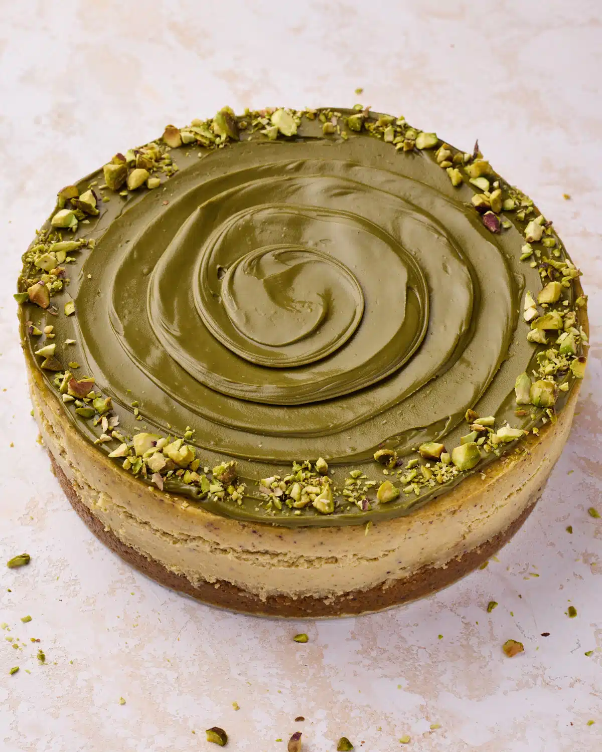 Pistachio cheesecake decorated with a swirl of pistachio cream and chopped pistachios around the outside. 