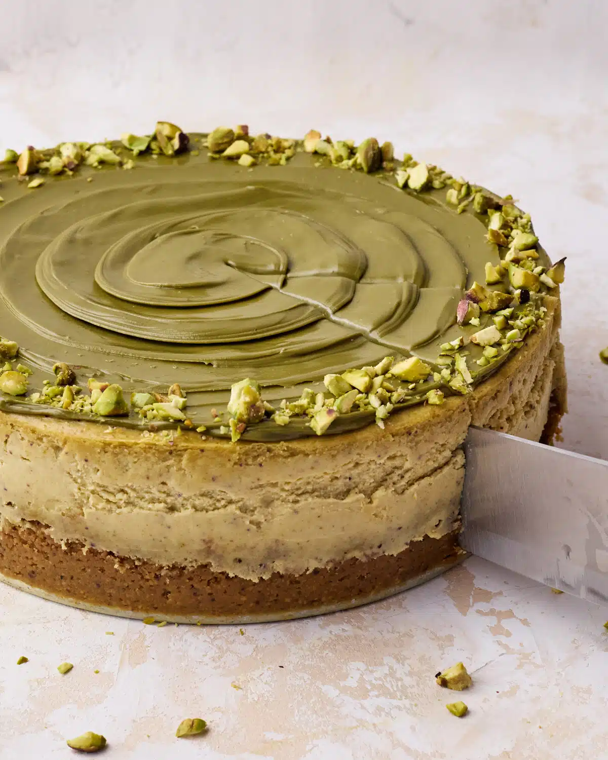 Pistachio cheesecake being sliced with a knife. 