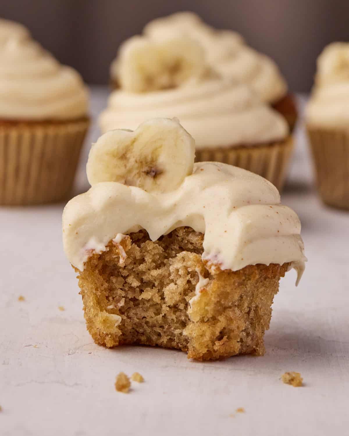 Banana cupcake with a bite taken out of it to show how moist and fluffy it is.