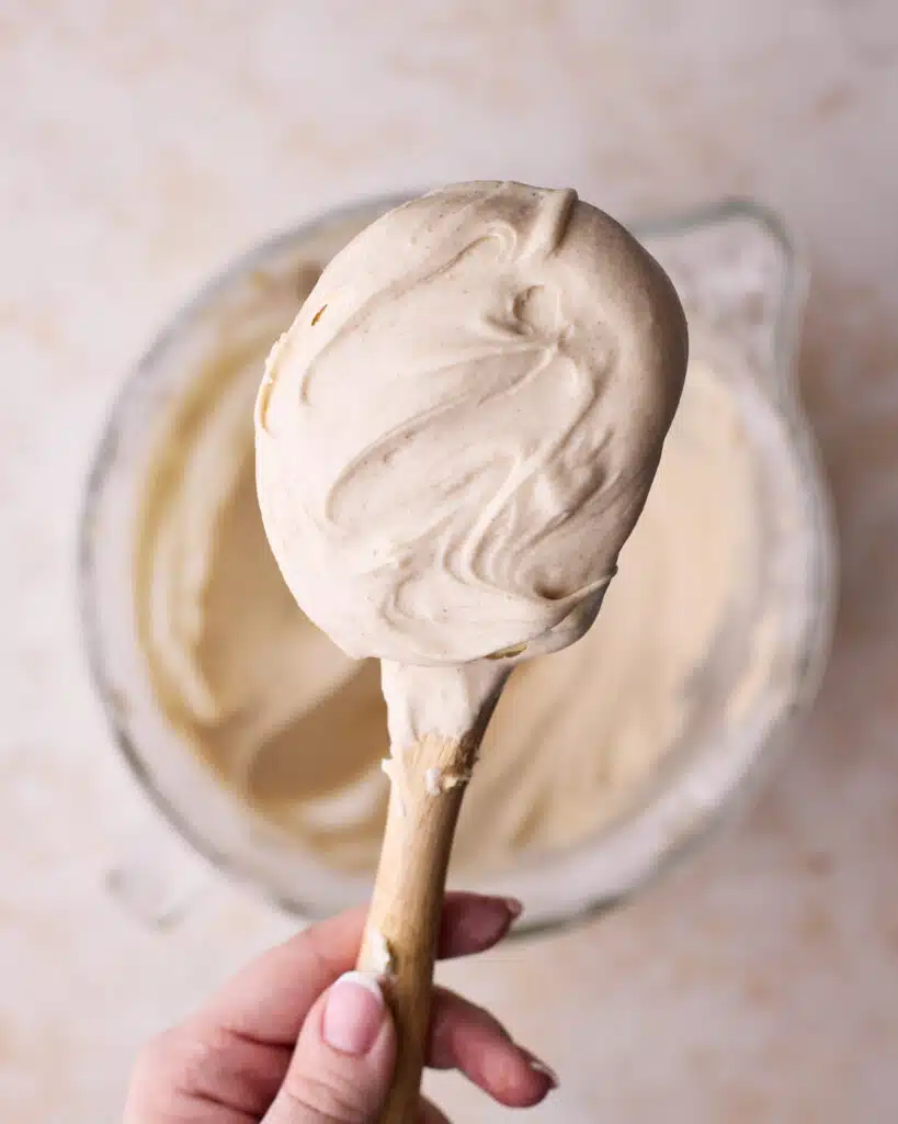 Cream cheese frosting on a spatula to show the soft and creamy texture.