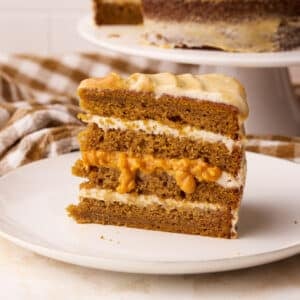 Slice of pumpkin cake showing layers of cinnamon cream cheese frosting and pumpkin curd.