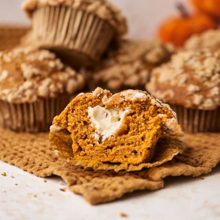 Pumpkin cream cheese muffin cut in half to reveal surprise cheesecake filling.