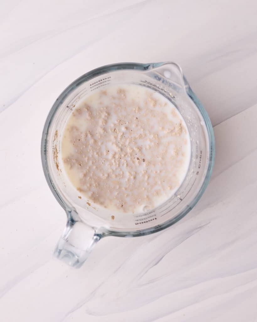 Activating active dry yeast in a jug with warm milk and sugar to make sure it is alive.