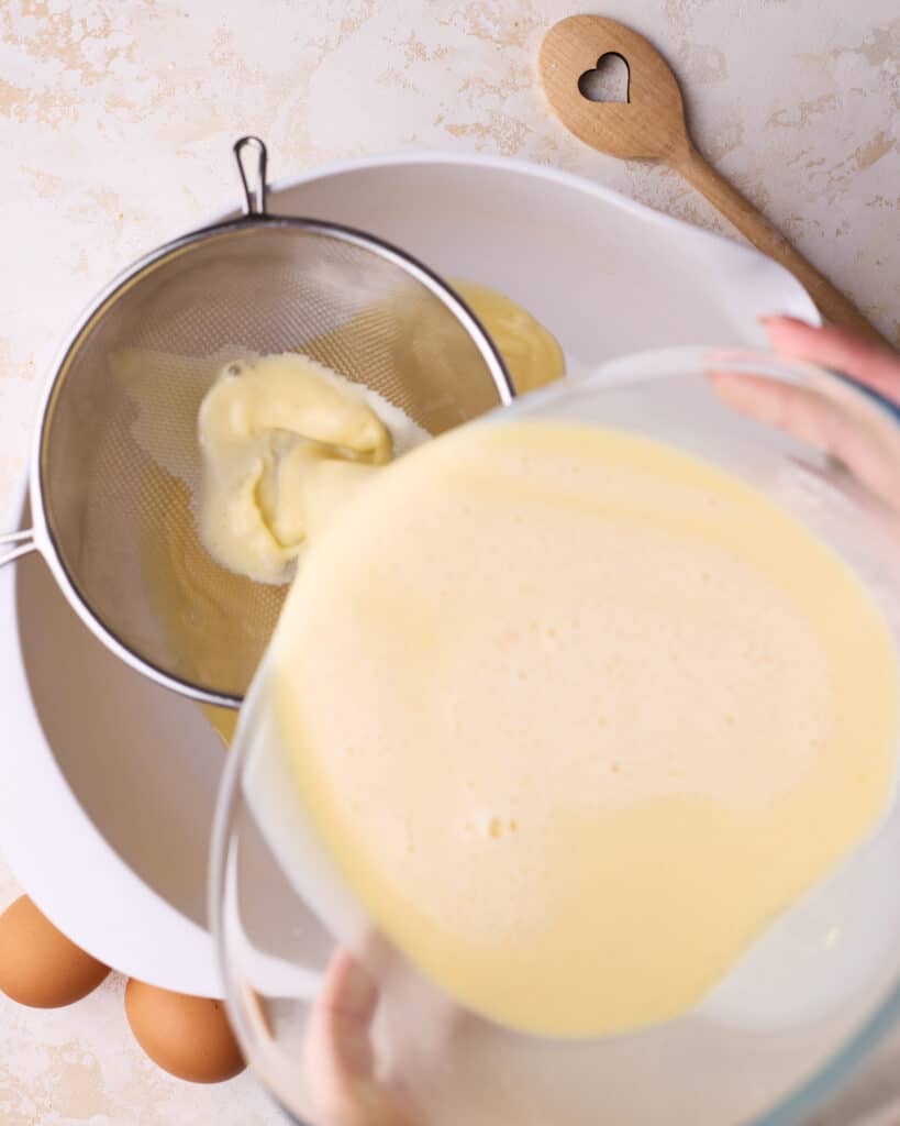 Pouring custard filling through a fine mesh sieve to remove any pieces of coagulated egg. 