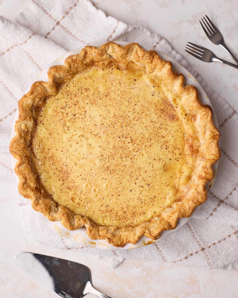 Baked egg custard pie in flaky pie crust with nutmeg sprinkled on top. 