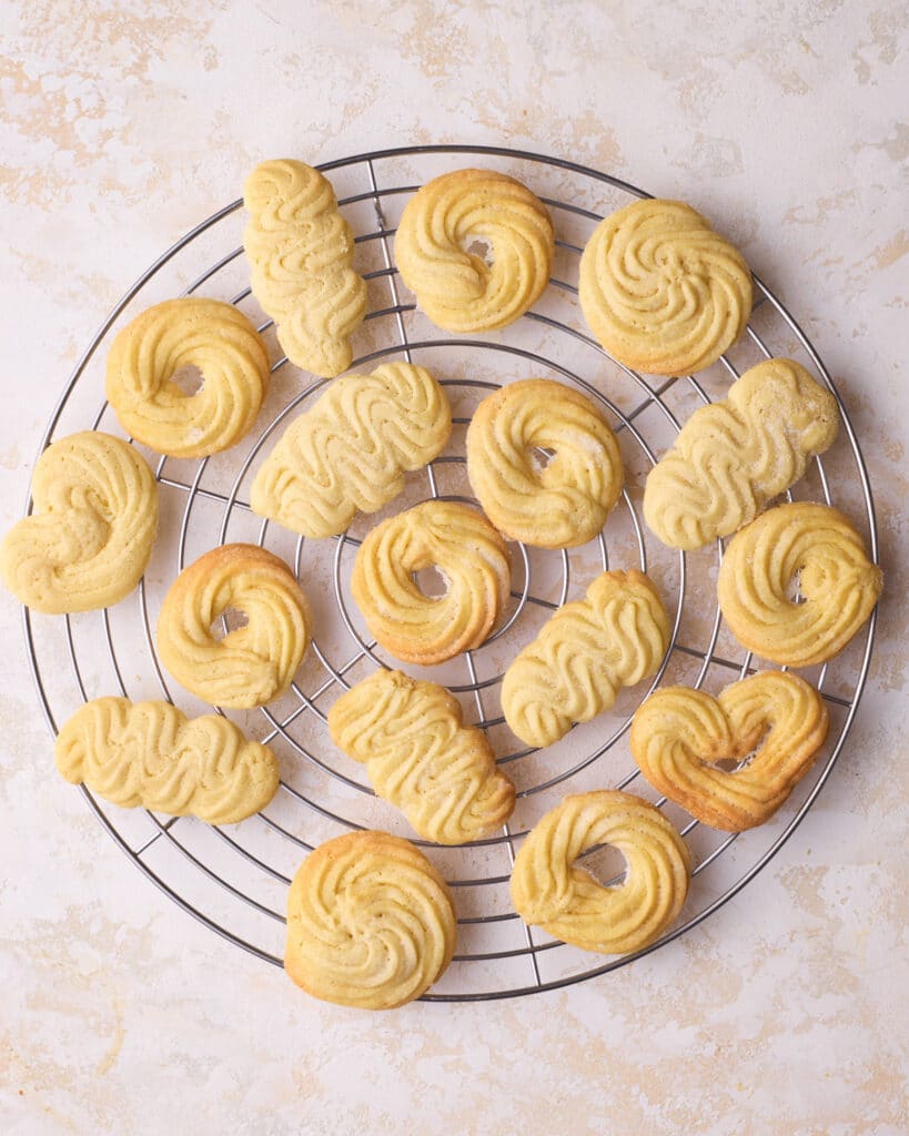 A whole batch of baked Danish butter cookies cooling on a wire rack. 