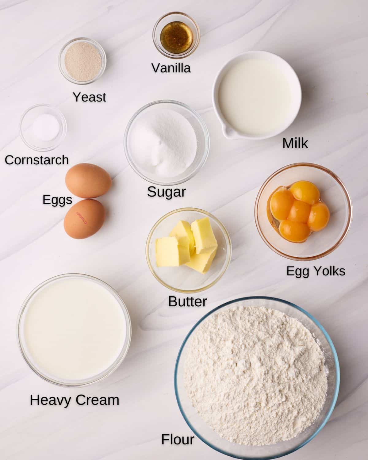 Ingredients to make Bavarian cream donuts - flour, eggs, sugar, butter, yeast, milk, egg yolks, cornstarch, vanilla, milk and heavy cream. 