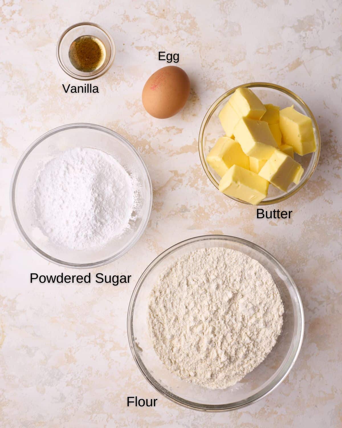 Ingredients to make homemade Danish butter cookies - butter, powdered sugar, flour, egg and vanilla extract. 