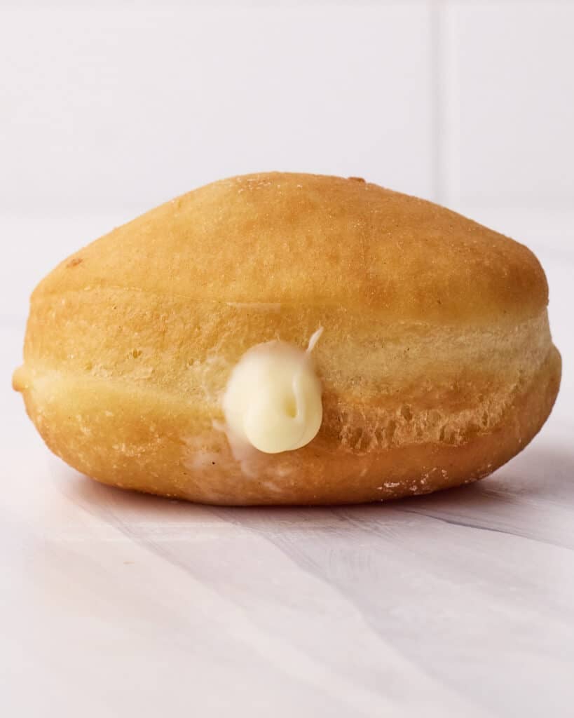 Side view of a homemade donut that has just been filled with custard filling. 