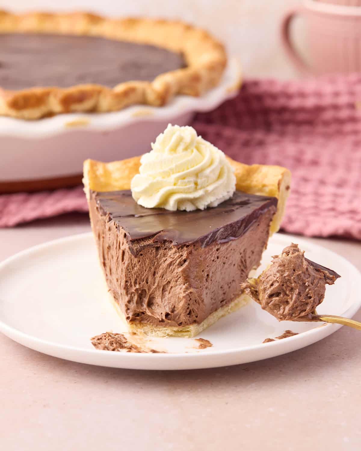 Slice of chocolate mousse pie with a bite taken out of it to show the creamy chocolate filling and flaky pie crust underneath. 