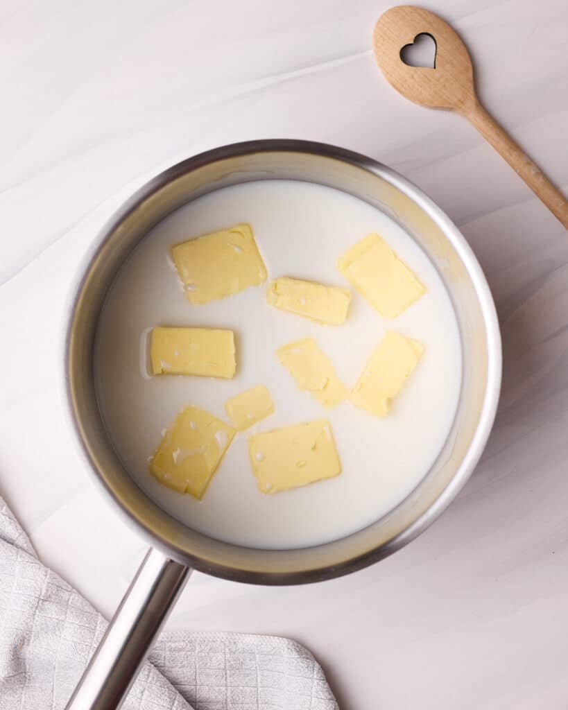 Butter, milk, water, and salt in a saucepan to make choux pastry - the butter is cut into small pieces so it can melt faster. 