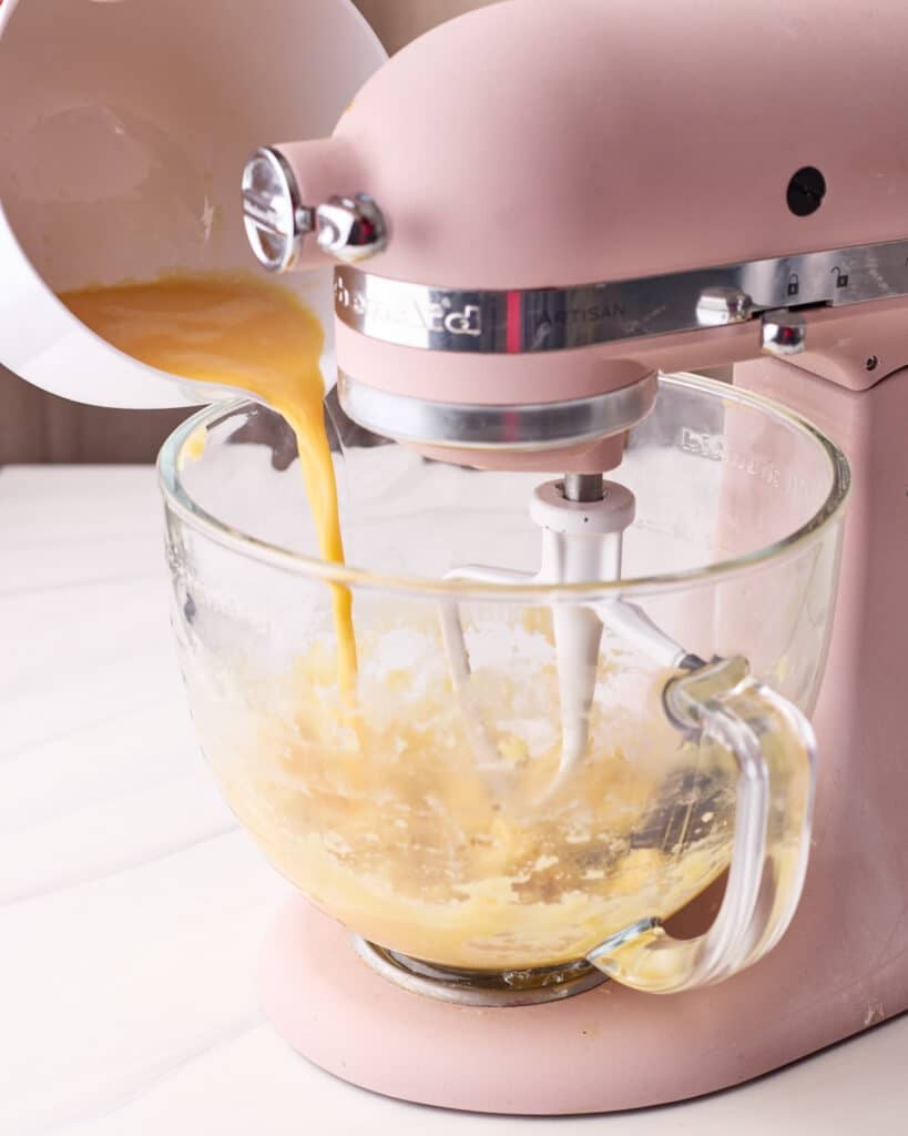 Pouring eggs into a stand mixer gradually to make choux pastry. 