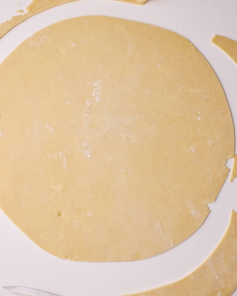 A large circle of pie dough. being cut to give neat edges on the pie crust. 