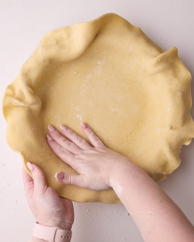 Lining a pie dish with flaky pie dough.