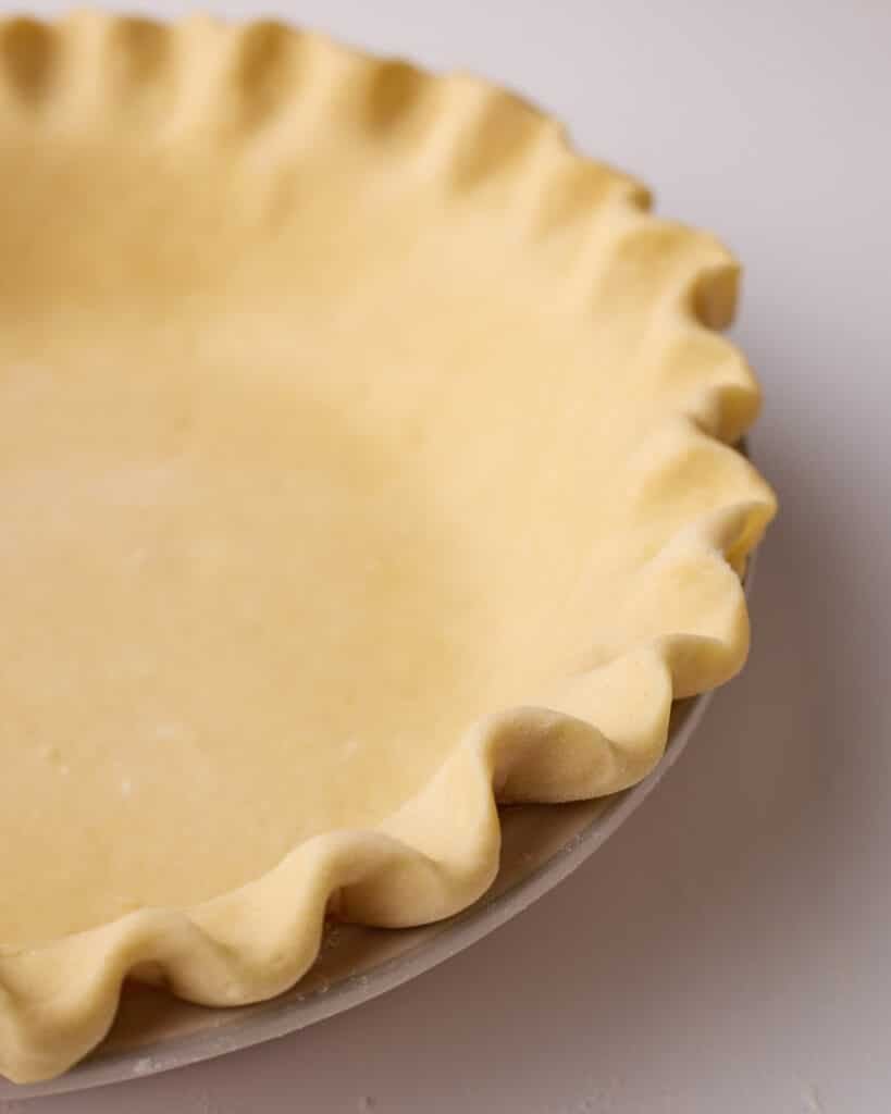 Close up of the edge of a pie crust with scalloped crimped edges.