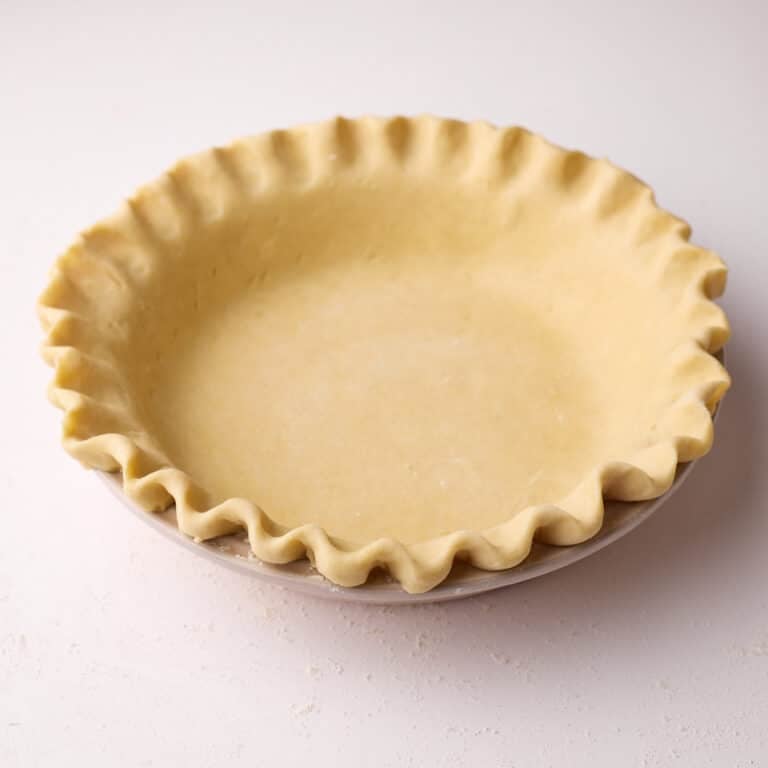 Homemade pie crust, unbaked in a pie dish with crimped edges.