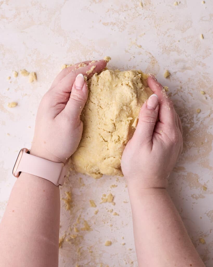 Bringing homemade pie dough together in hands. 