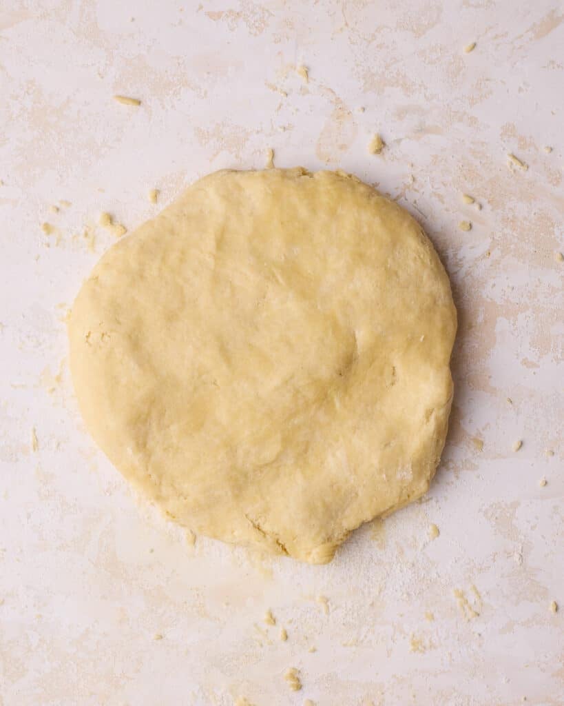 Homemade pie dough being flattened out into a disk to make flaky pie crust. 