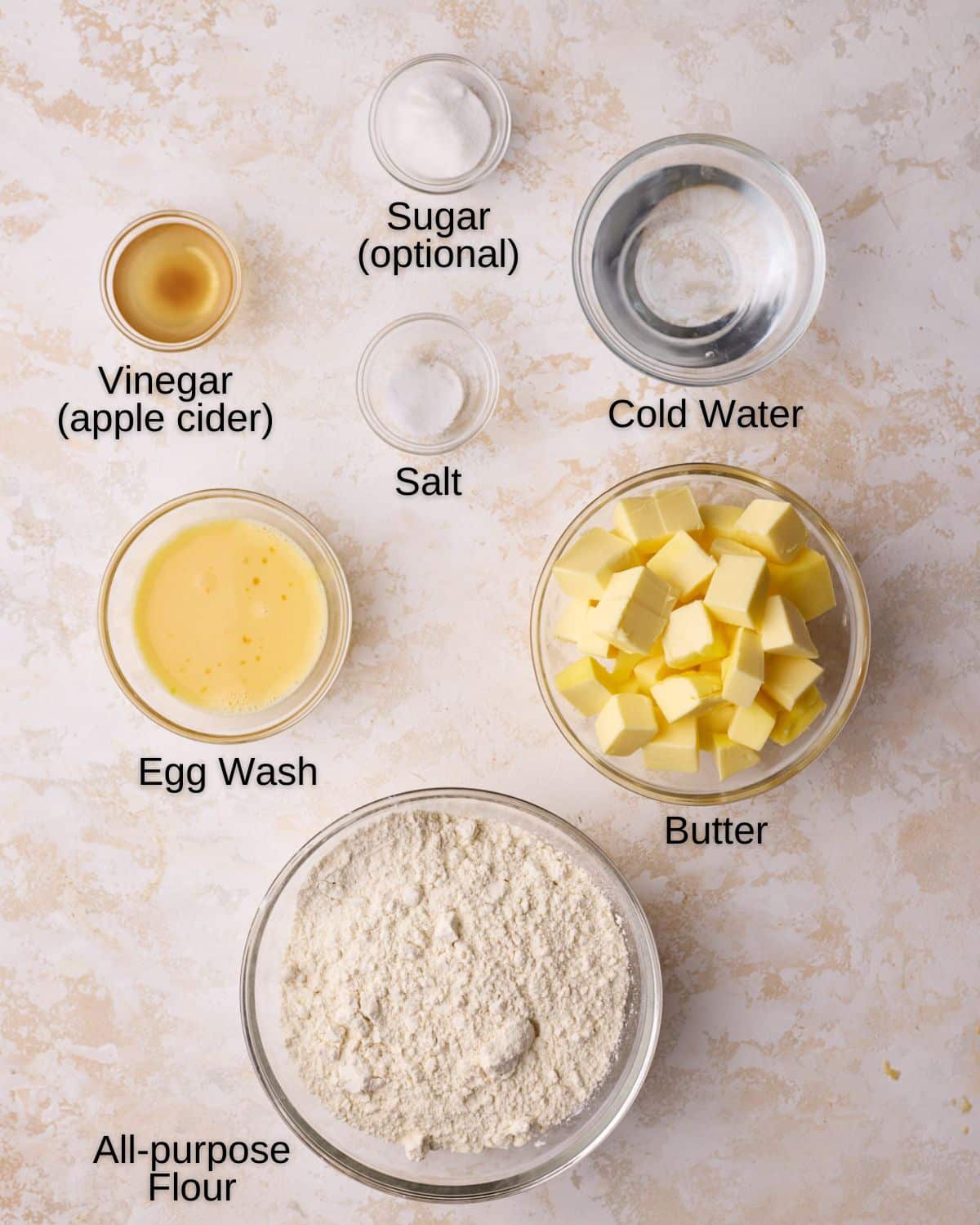 Ingredients to make homemade pie dough - flour, butter, salt, cold water, vinegar and sugar. 