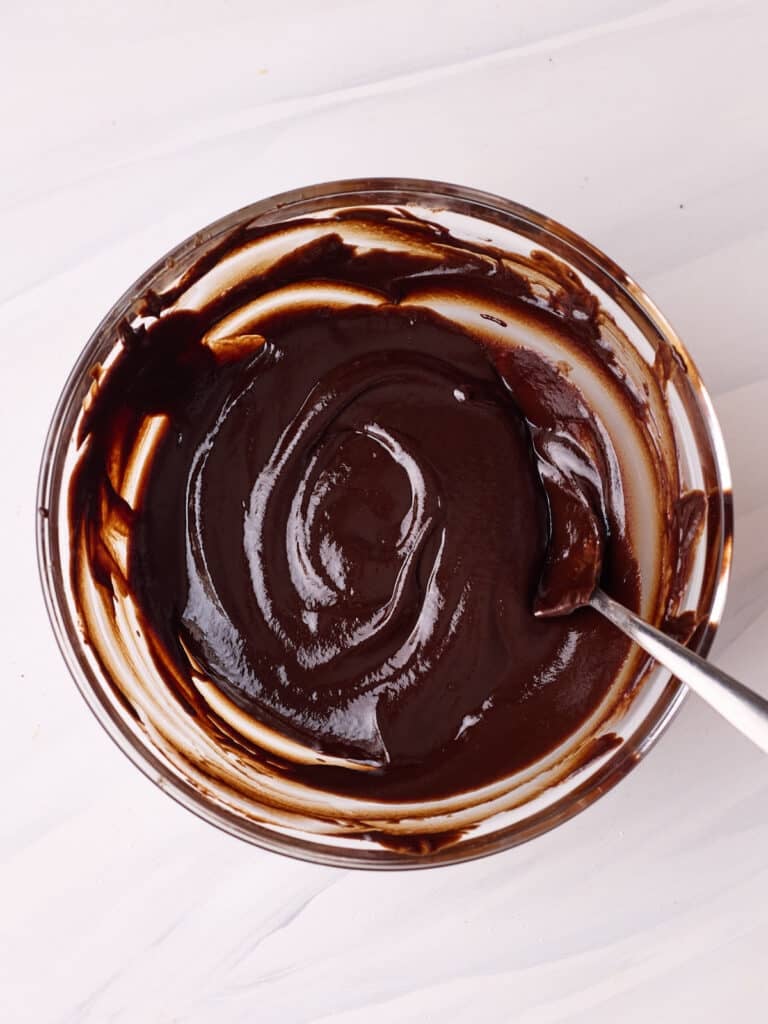 Chocolate glaze for profiteroles in a glass bowl. 