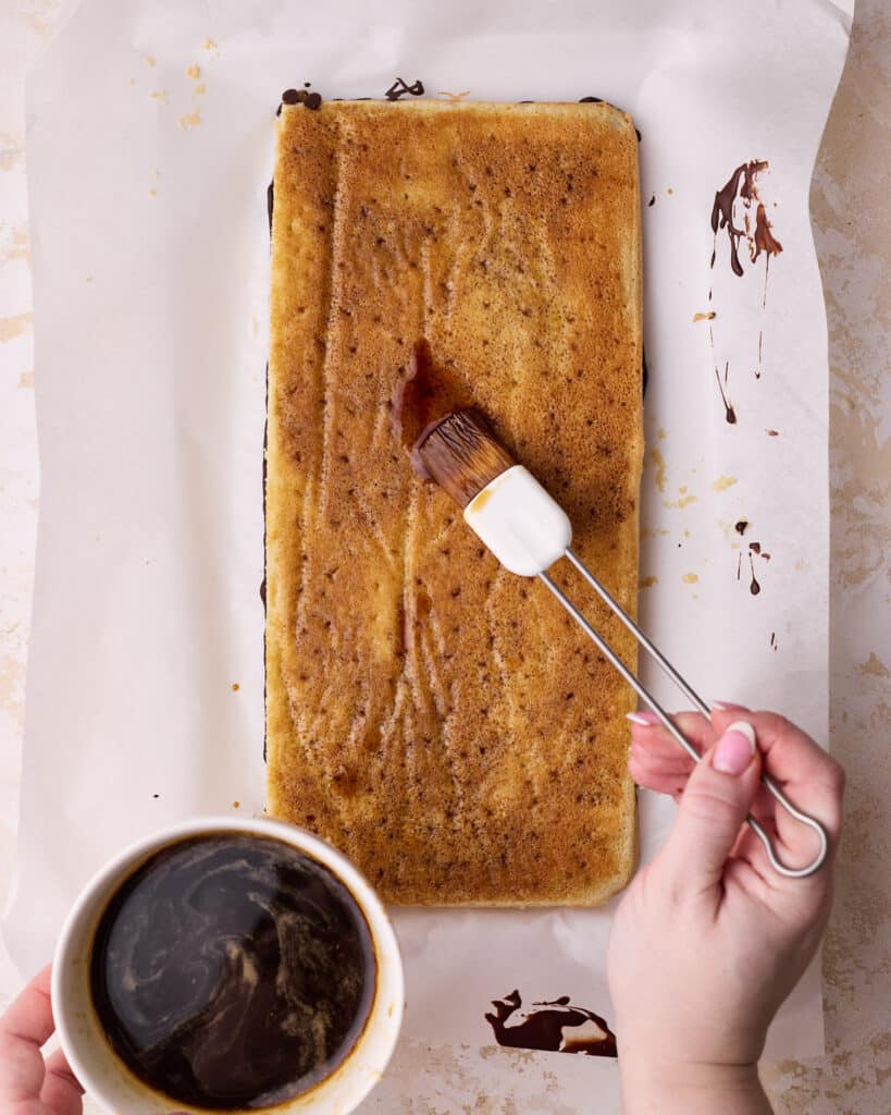 Brushing coffee syrup onto joconde sponge cake to make the first layer of an opera cake. 