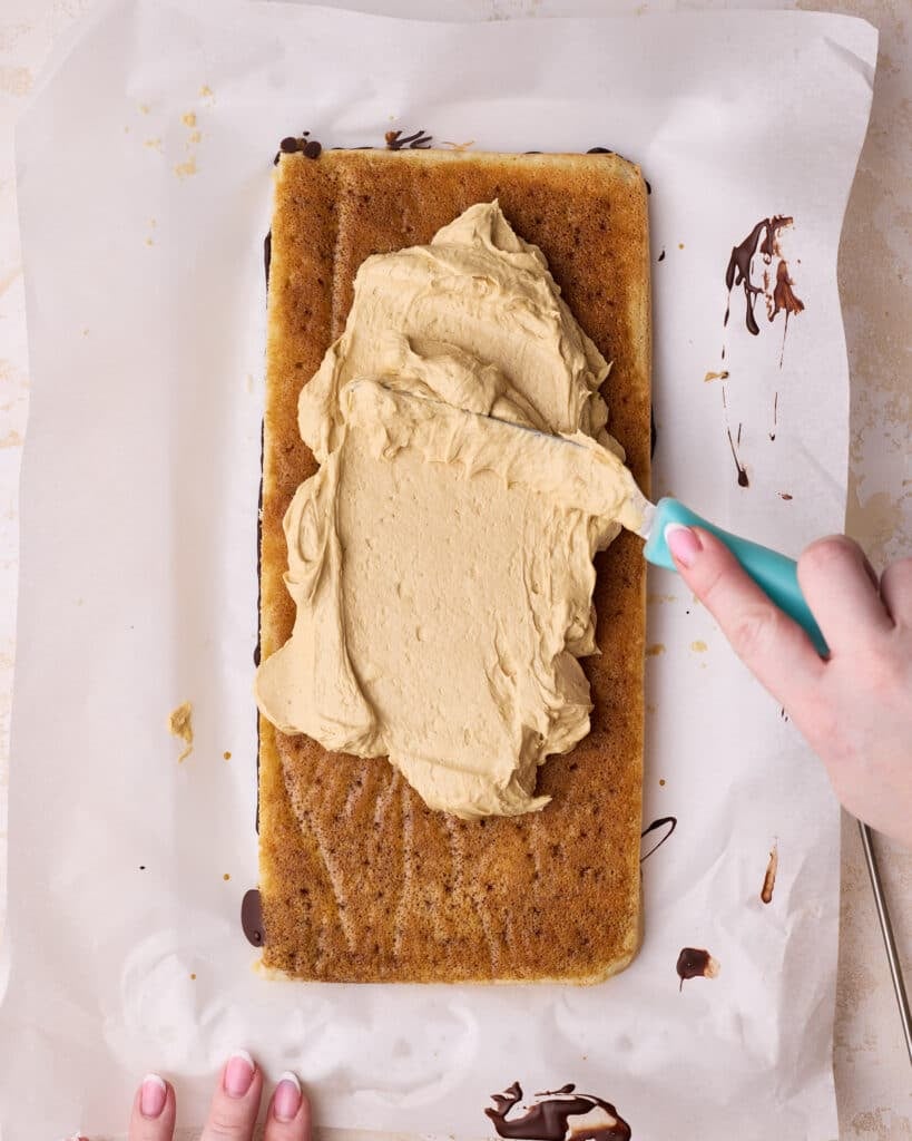 Spreading coffee flavored French buttercream onto joconde sponge soaked in coffee syrup to make Opera cake. 