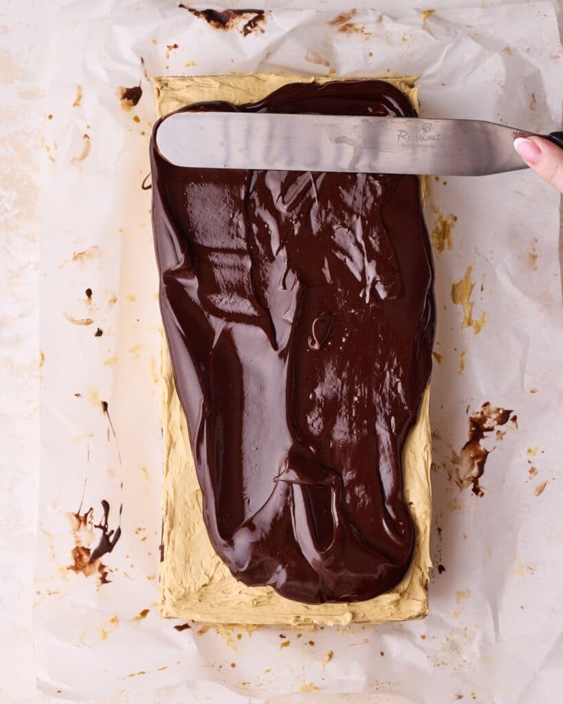 Spreading shiny chocolate glaze on top of Opera cake. 