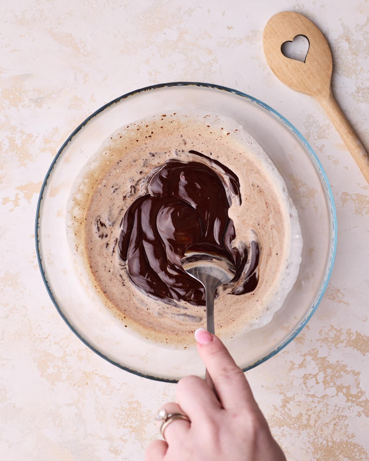 Making glossy chocolate ganache in a glass bowl.
