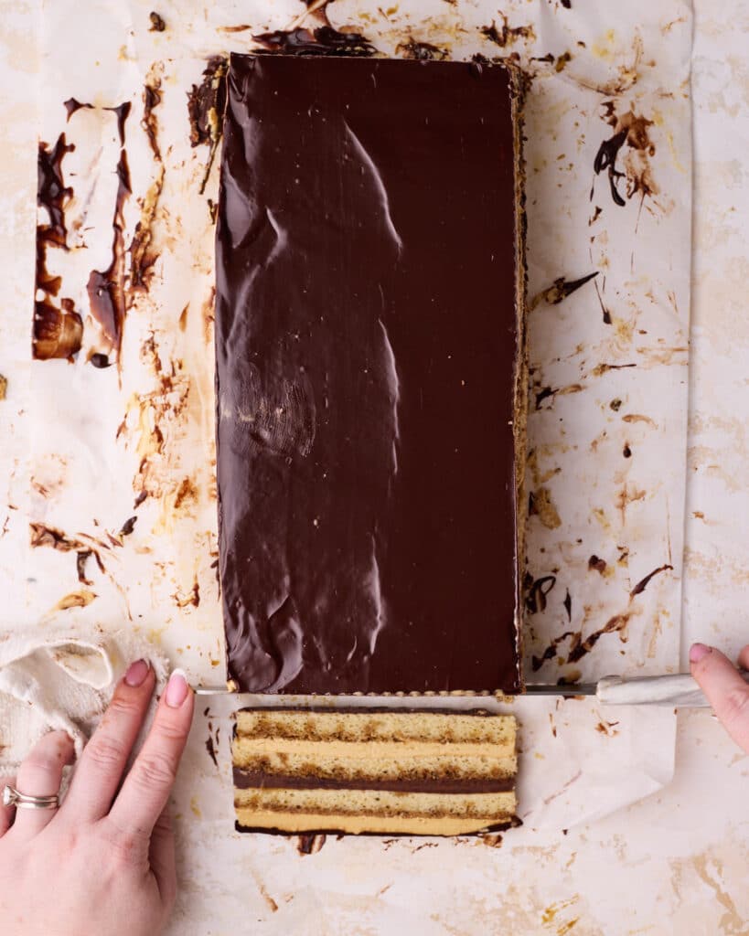 Trimming the edges off of an opera cake to show beautiful layers inside. 