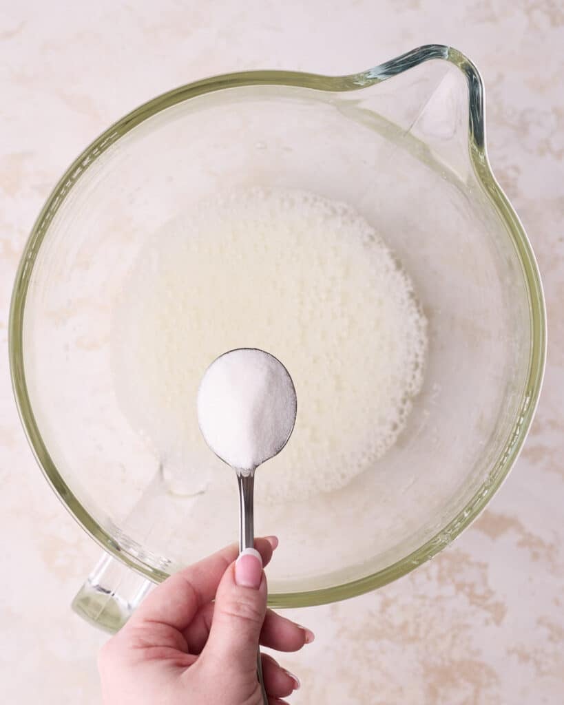 Adding sugar to whipped egg whites, one tablespoon at a time to make meringue. 