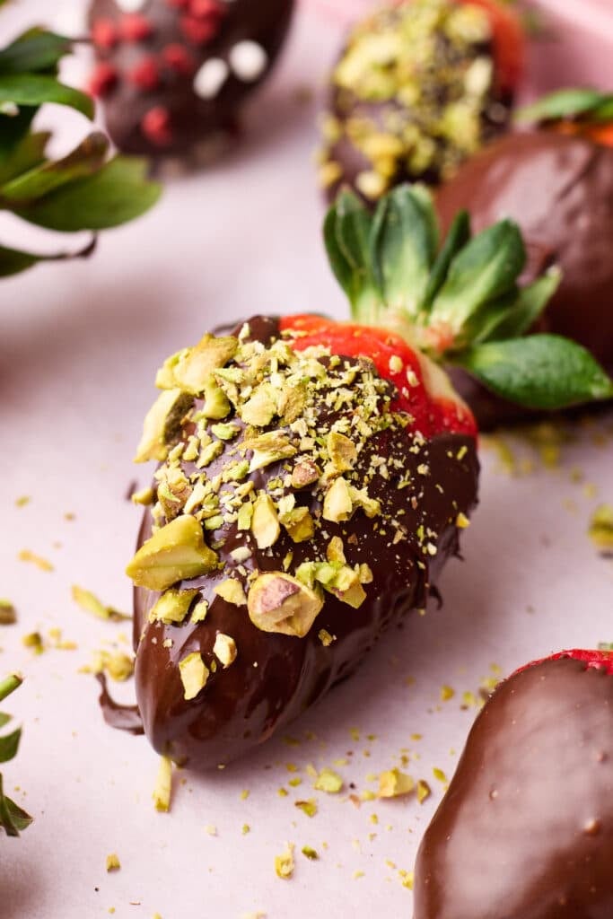 Chocolate covered strawberry with chopped pistachios sprinkled on top. 