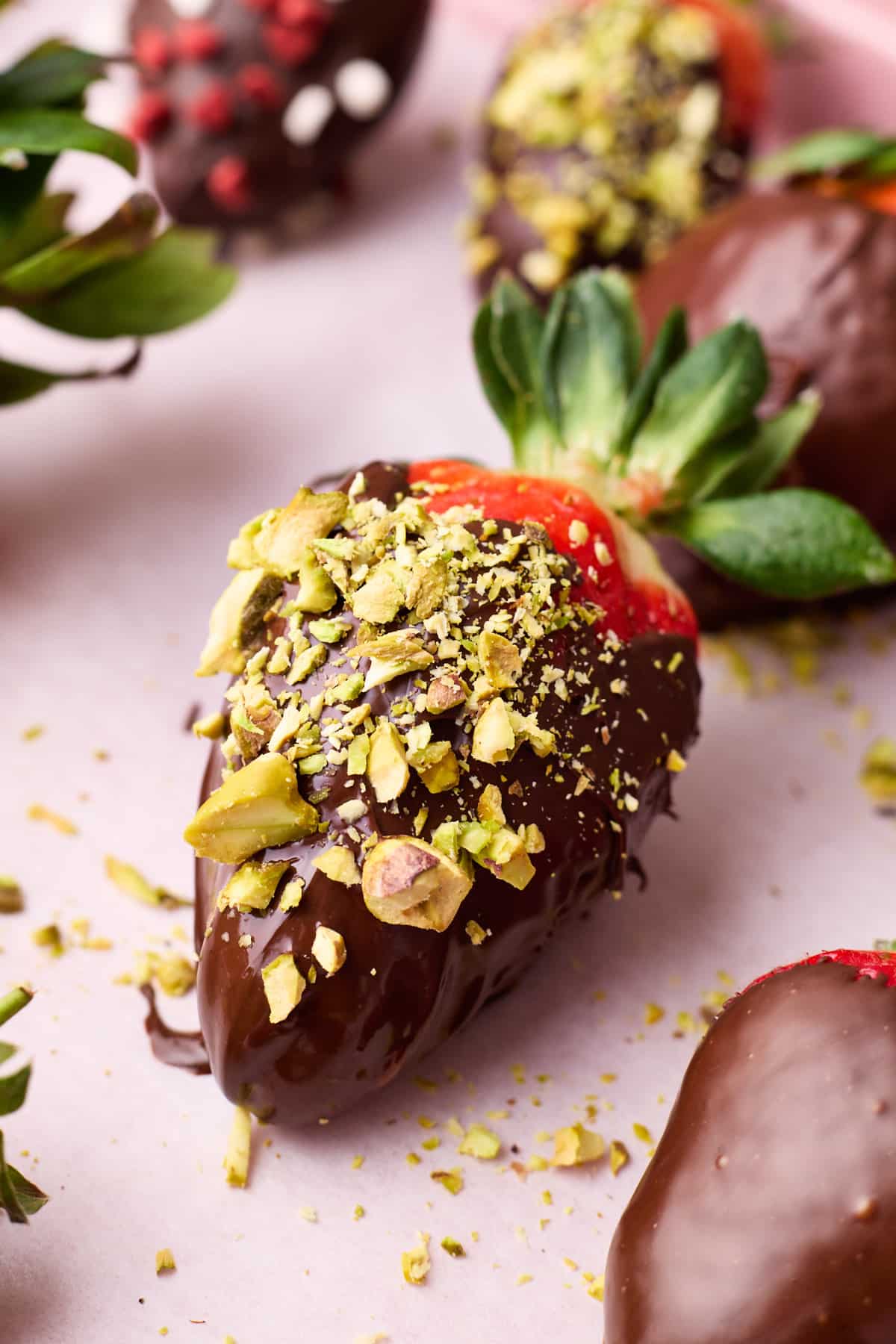 Chocolate covered strawberry with chopped pistachios sprinkled on top.