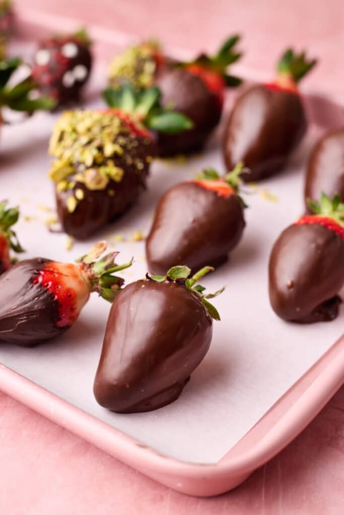 Chocolate covered strawberries sitting on a tray to set.