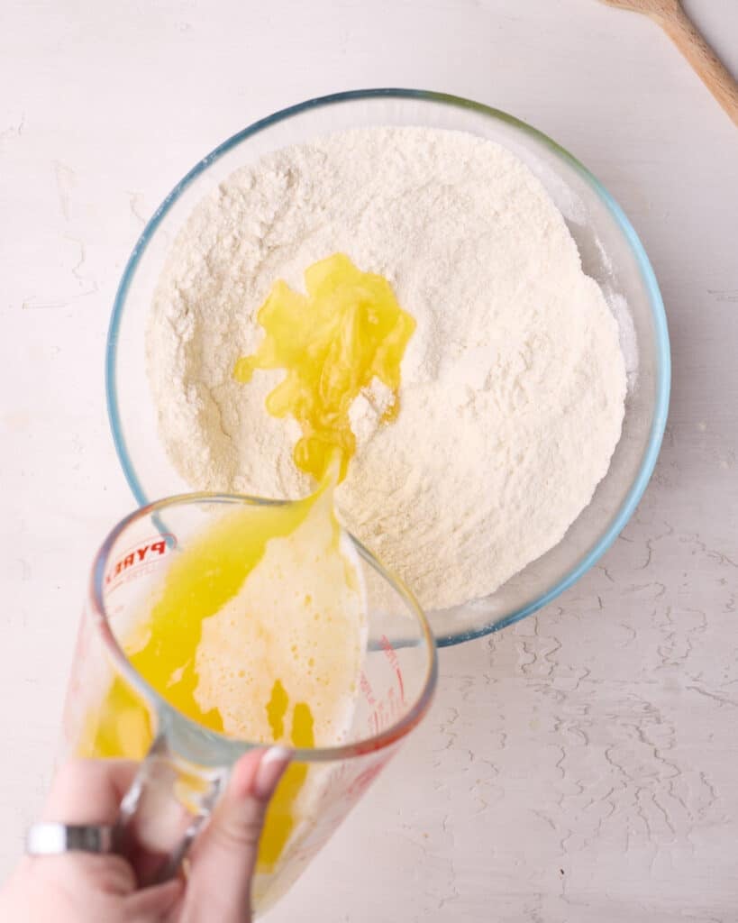 Pouring melted butter into flour and sugar to make crumble topping. 